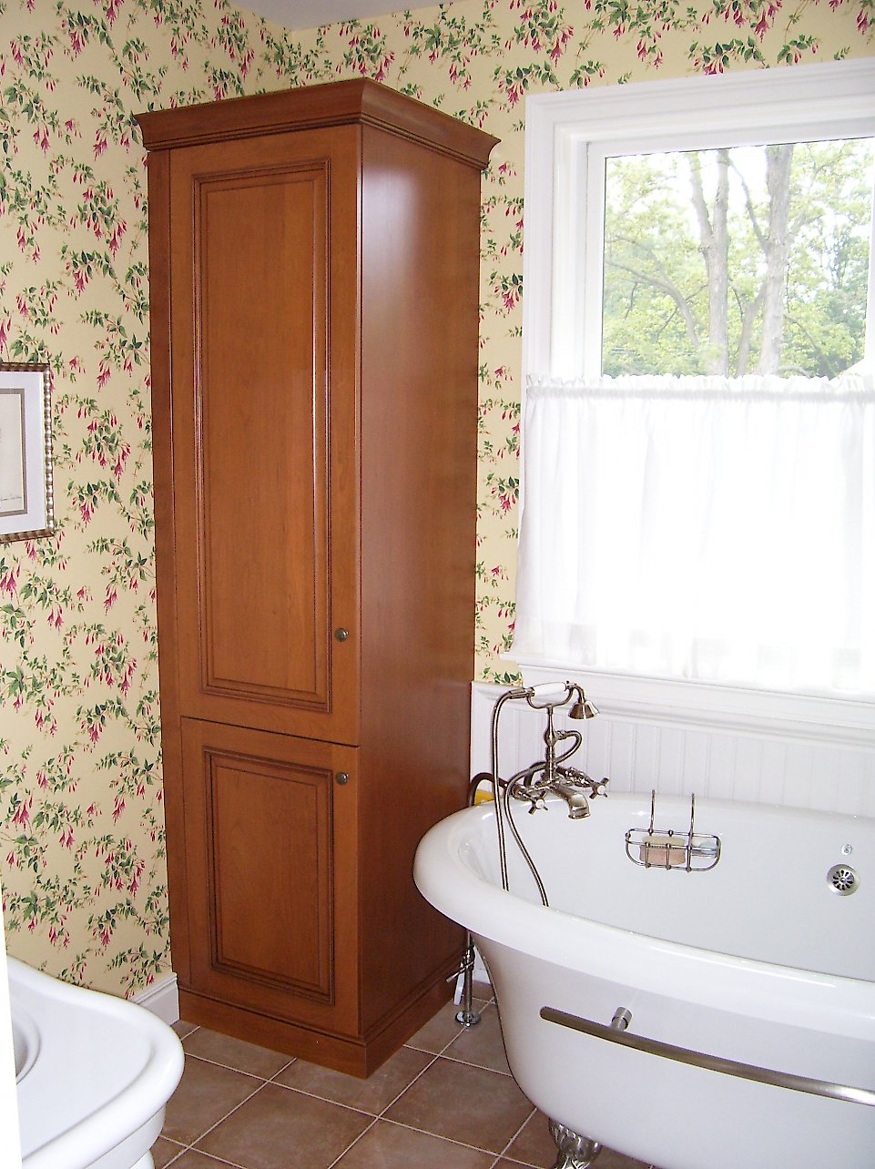 Cherry linen cabinet next to the tub.